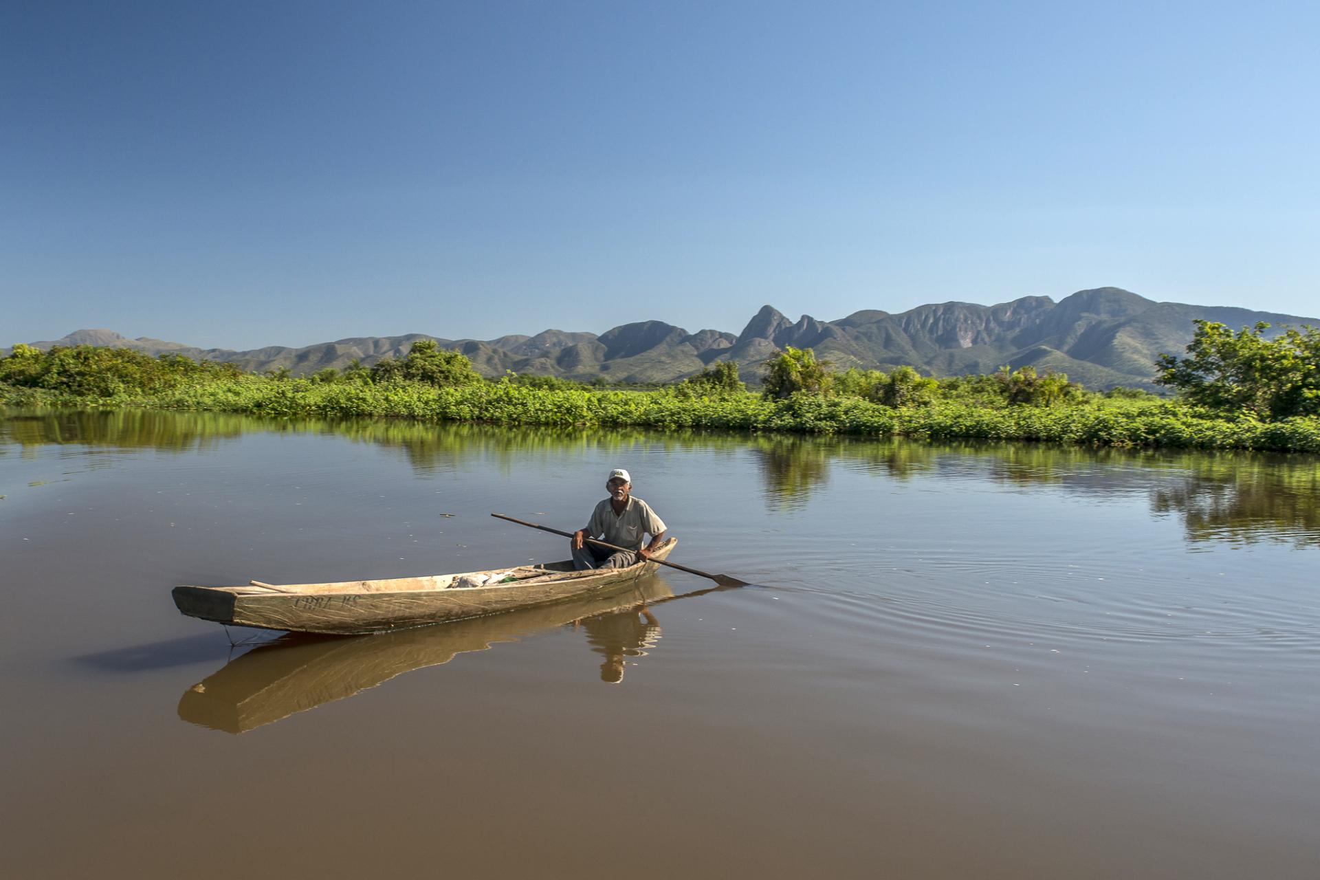 Mit einem Boot fährt ein Mann durch eine überschwemmte Landschaft im Süd-Pantanal Überschwemmte Landschaft im Süd-Pantanal