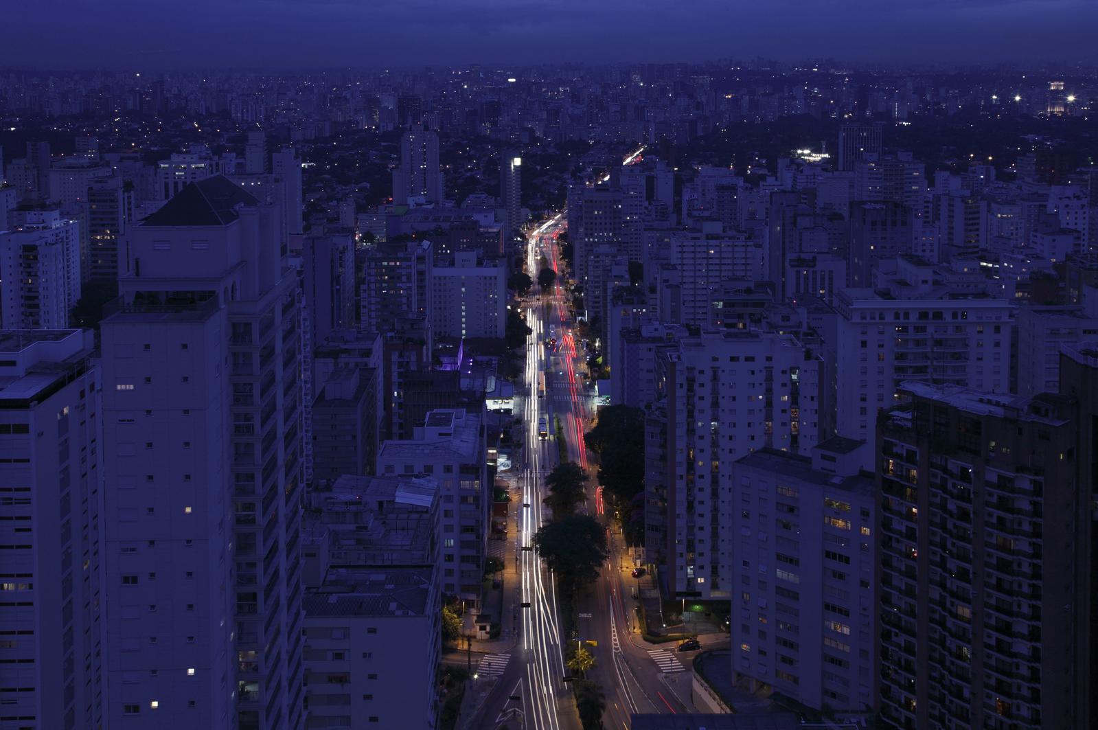 Nächtlicher Blick auf die Avenida Paulista in São Paulo, gesäumt von Hochhäusern und durchzogen von Lichterspuren des Verkehrs