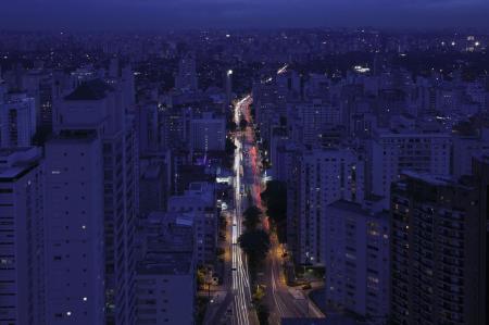 Nächtlicher Blick auf die Avenida Paulista in São Paulo, gesäumt von Hochhäusern und durchzogen von Lichterspuren des Verkehrs