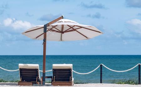 Zwei Liegestühle mit Sonnenschirm am Strand – was Sie für einen perfekten Strandtag in Brasilien einpacken sollten.