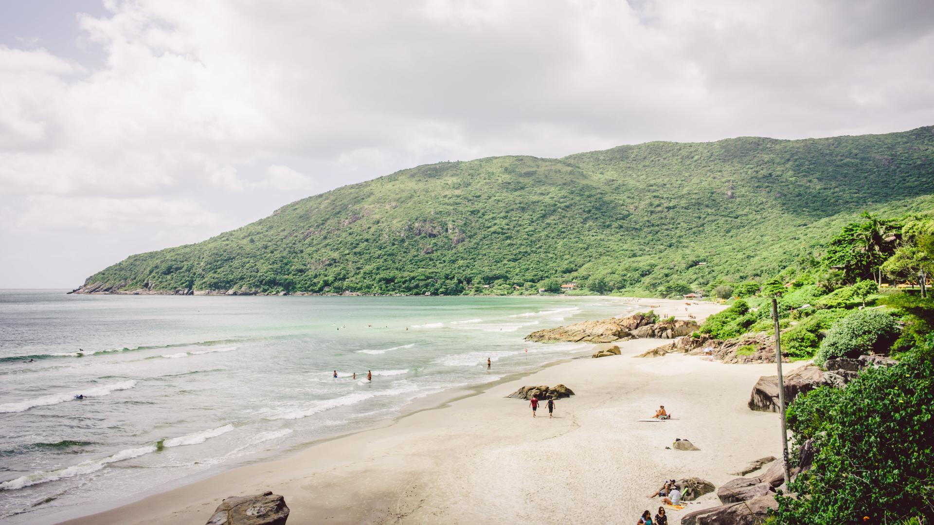 Praia do Matadeiro – Naturstrand in Florianópolis, Brasilien Blick auf den Praia do Matadeiro in Florianópolis mit weißem Sandstrand, grünen Hügeln und sanften Wellen