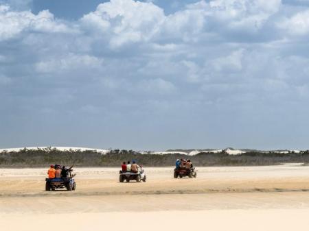 Drei Buggys fahren hintereinander über den Sandstrand