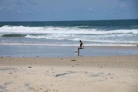 Junger Mann spielt Fußball am Strand von Itacare