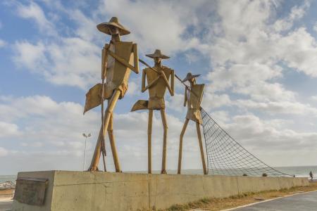 Drei Statuen mit einem Fischernetz im Vordergrund im Hintergrund der Atlantik
